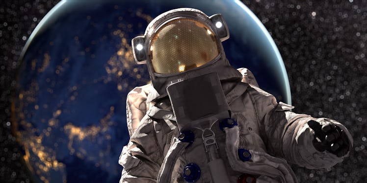 A close up portrait of an astronaut in full space suit holding out one hand whilst on a space walk w...