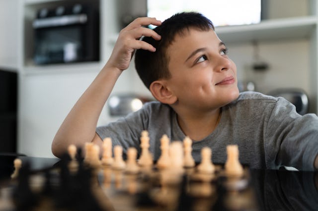 Pensive and smiling boy playing chess