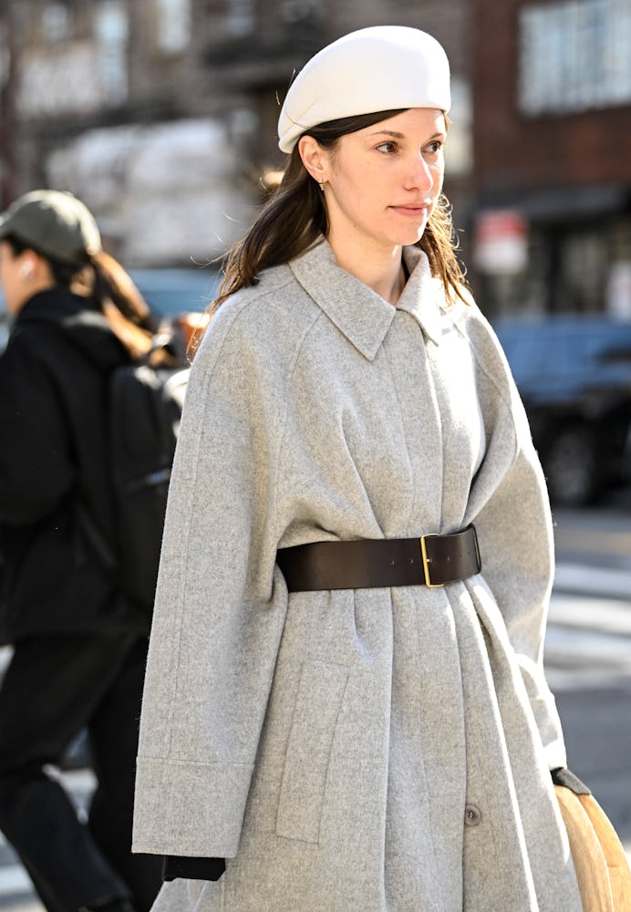 NEW YORK, NEW YORK - FEBRUARY 09: Laura Reilly is seen wearing a gray coat, black belt, cream bag, w...