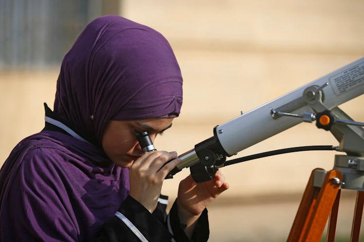 A student at Baghdad University uses a telescope to observe a partial solar eclipse in Iraq's capita...