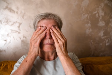 tired senior woman covered her eyes with her hands