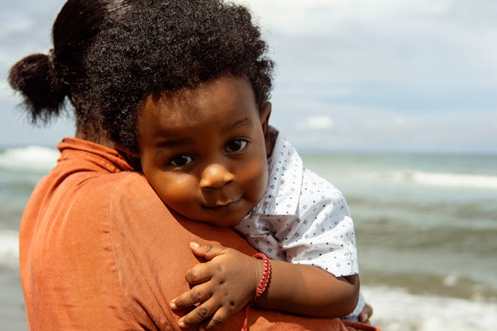 Adult woman mother holding a new born baby in the beach.