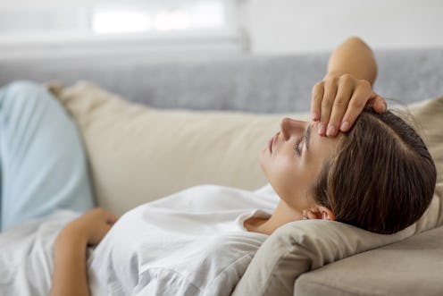 woman laying on sofa eyes closed feeling unwell
