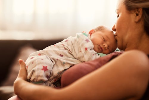 Cute newborn baby sleeping in her mother's arms while she kisses her head, in a story about a viral ...