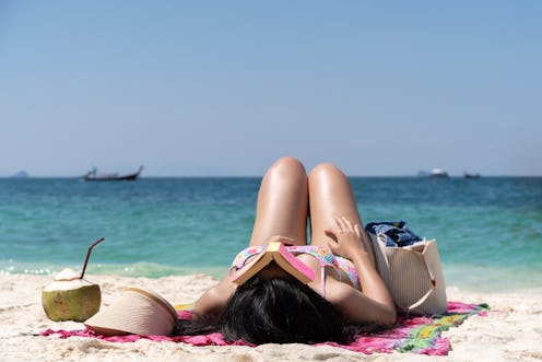 Woman relaxing on the beach, she was wearing a swimsuit and a sun hat. and she is sleeping. The beac...