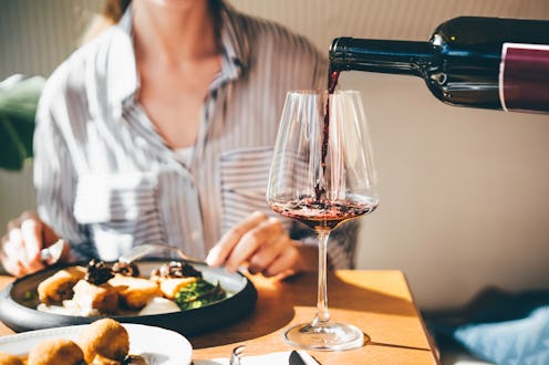 Waiter pouring red wine for customers in restaurant.
