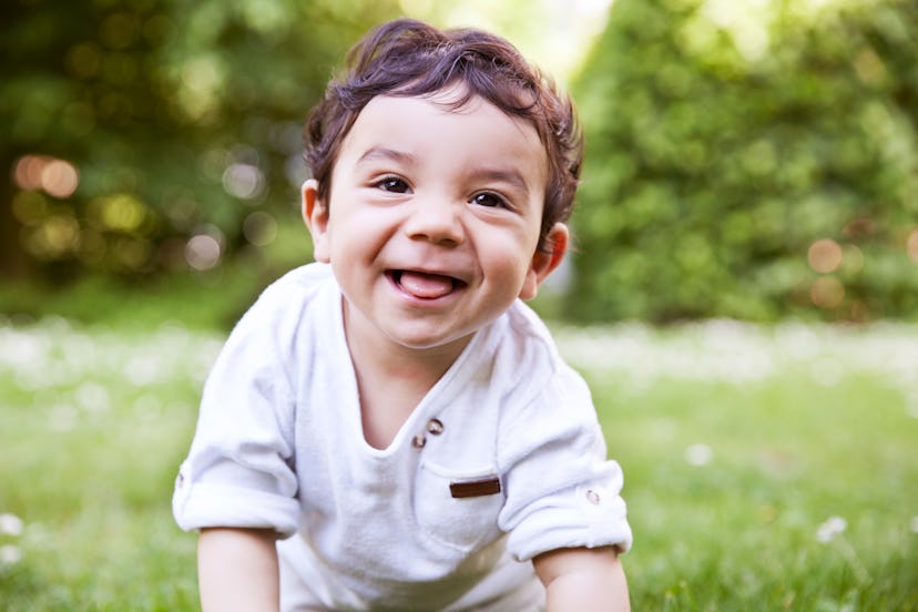Baby boy crawls through grass smiling in a list of gaelic baby boy names