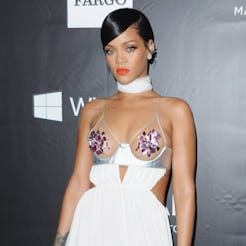 Rihanna wears a white gown with a sheer bra top to the 2014 amfAR LA Inspiration Gala at Milk Studio...