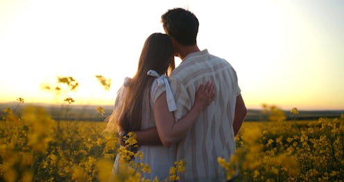 Travel, sunset and couple in canola field walking on vacation, holiday or weekend trip. Adventure, n...