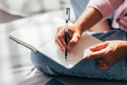 A close-up photo capturing a person's hands as they write in a ruled notebook, possibly for planning...