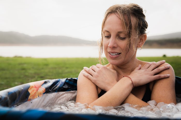 Woman inside a iced bath tube inhaling with eyes closed, in a story about whether it's safe or not t...