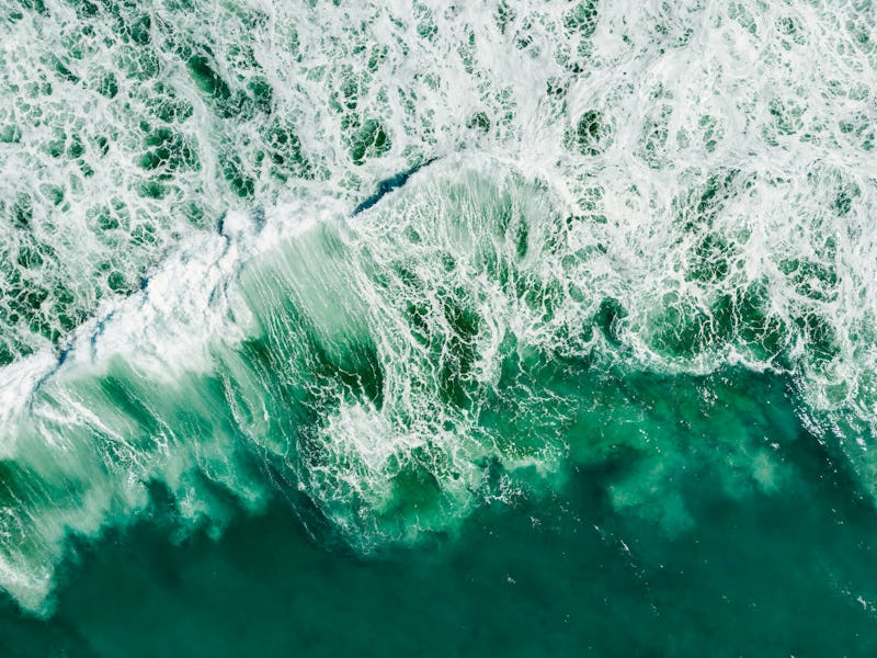 Aerial view of vortex created by waves of the rough ocean crashing on rocks