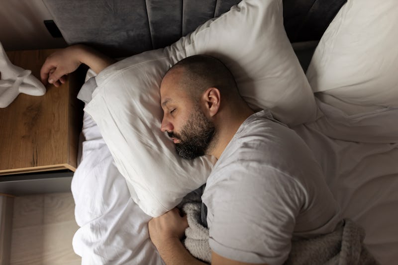 Bed, morning and relax man with beard sleeping, tired or nap for relief, wellness and rest in home, ...