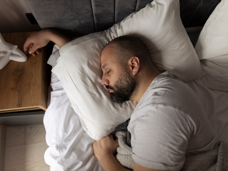 Bed, morning and relax man with beard sleeping, tired or nap for relief, wellness and rest in home, ...