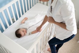 Mother putting baby to sleep in crib in a sleep sack. Amazon now bans the sale of weighted sleep sac...