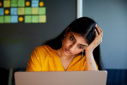 Young businesswoman looking frustrated while working online on a laptop at a table in a meeting room...