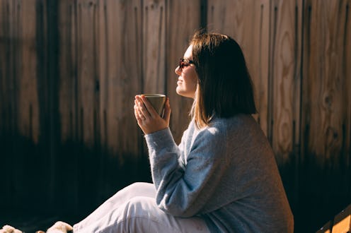 Side view of a calm woman sipping coffee, basking in warm sunlight with a wooden backdrop, emanating...