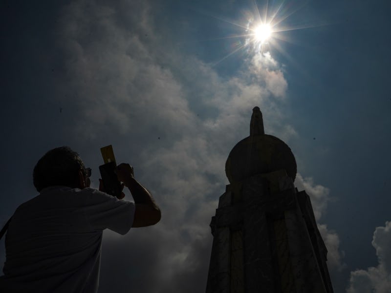 SAN SALVADOR, EL SALVADOR - 2023/10/14: A man takes a picture of a partial solar eclipse in San Salv...