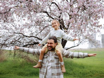 Concept of father's day! Happy family dad and child daughter back in nature. Blooming trees