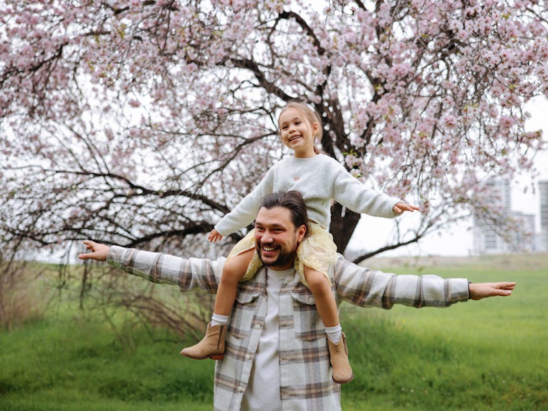 Concept of father's day! Happy family dad and child daughter back in nature. Blooming trees
