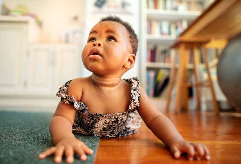 Baby girl crawling around on the living room floor of her home, in a list of powerful baby girl name...