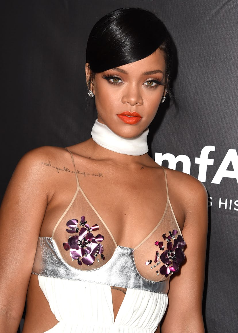 Rihanna wears a white gown with a sheer bra top to the 2014 amfAR LA Inspiration Gala at Milk Studio…