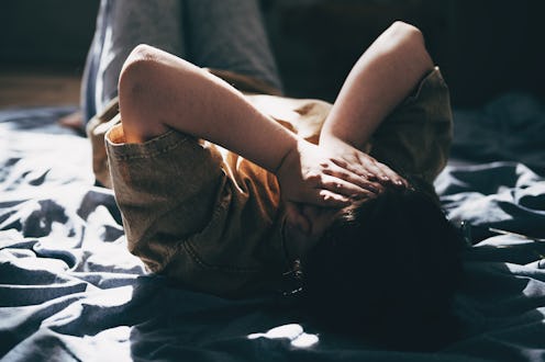 Upset teen girl sit on floor sadly look out window worried about teenage problem at school and commu...