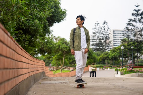 Mid-shot full body view of young Hispanic man skateboarding on Miraflores Boardwalk, Peru