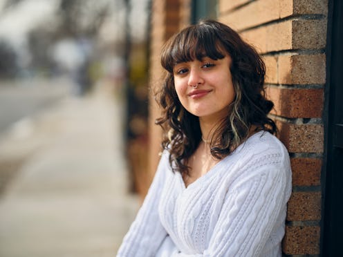 An outdoor portrait of a young hispanic woman standing on a downtown sidewalk.