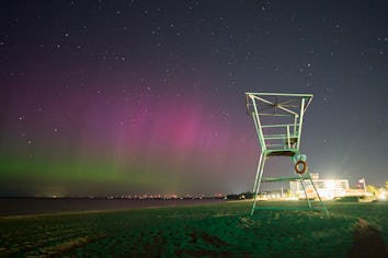 The Northern lights or aurora borealis illuminate the night sky at the beach in Grand Bend, Ontario,...