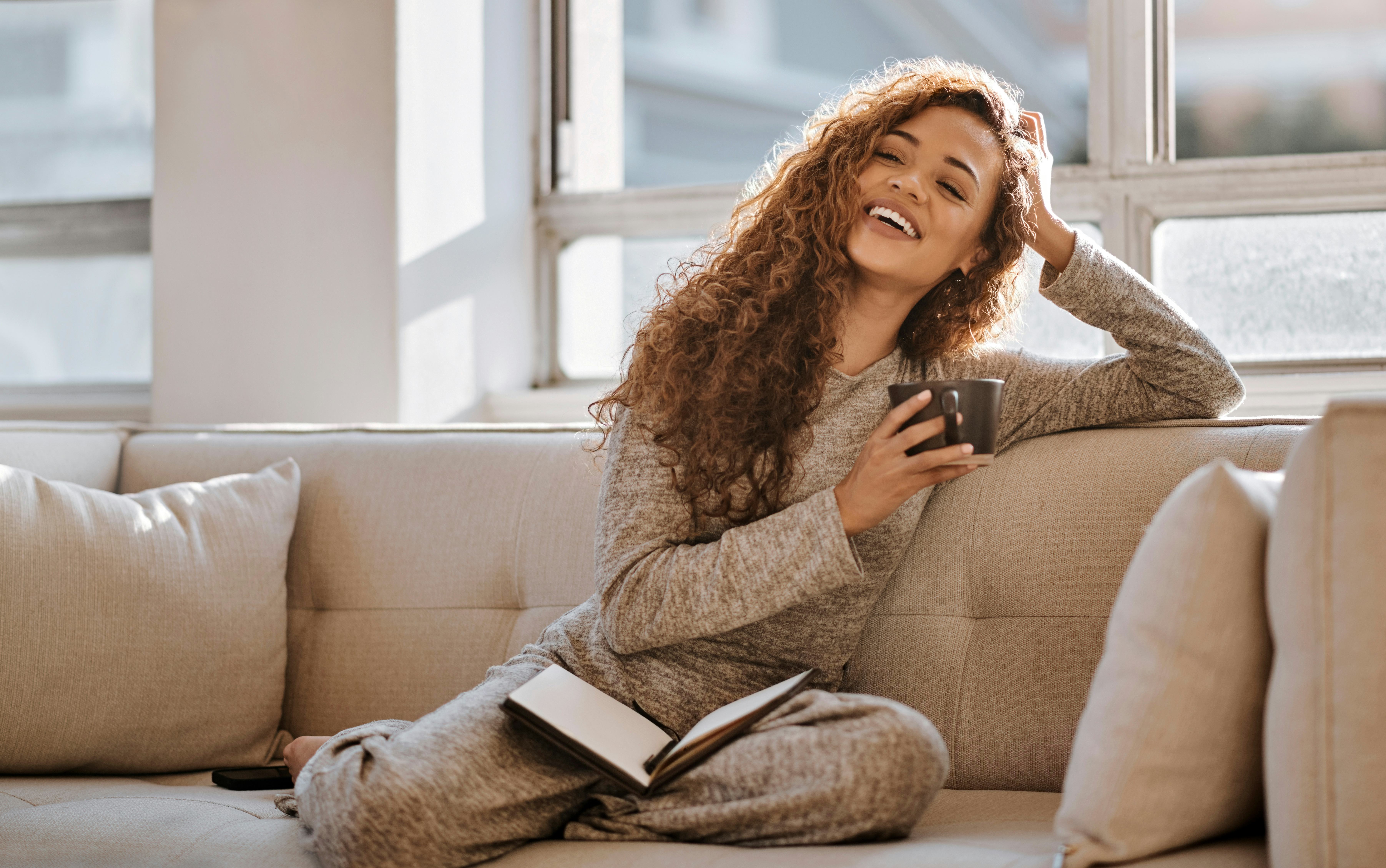 A smiling woman writing positive vibes quotes in her manifestation journal