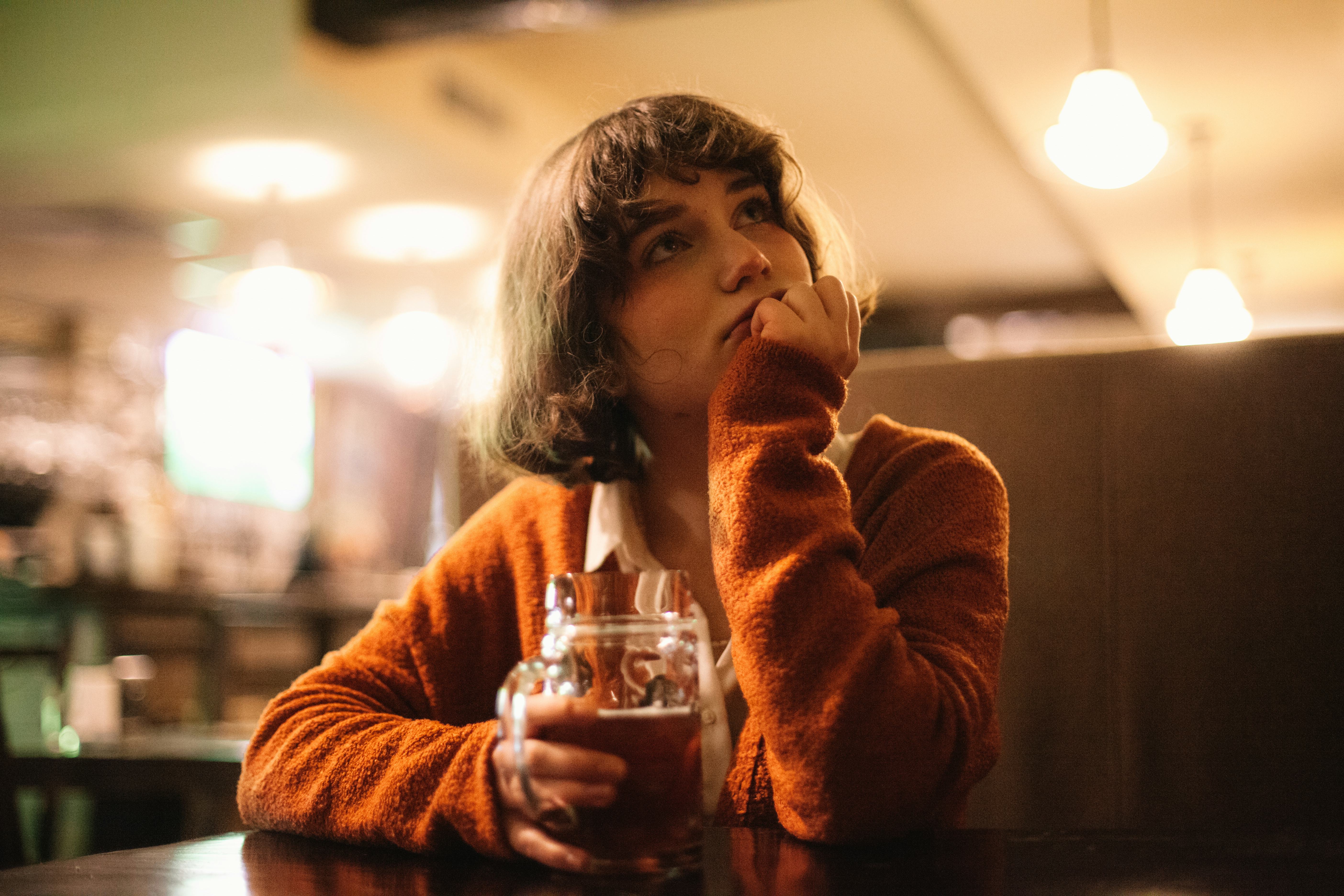 Woman at a bar thinking about the most insulting pickup lines women have heard