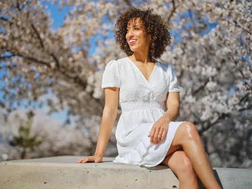 A portrait of a multiracial woman in springtime outdoors among cherry blossoms.