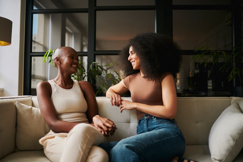 Two women on a couch making jokes for adults about relationships and friendships