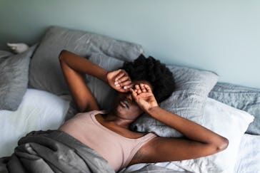 Young black woman yawning and rubbing eyes in the morning