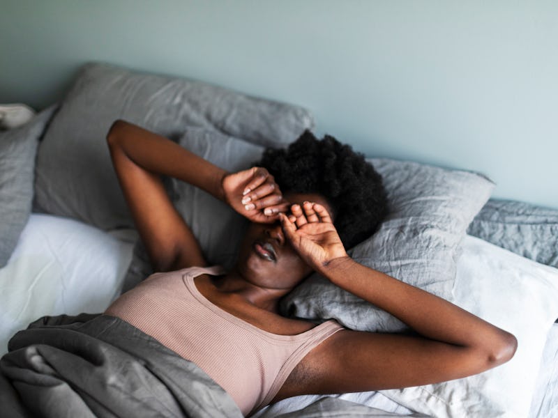 Young black woman yawning and rubbing eyes in the morning