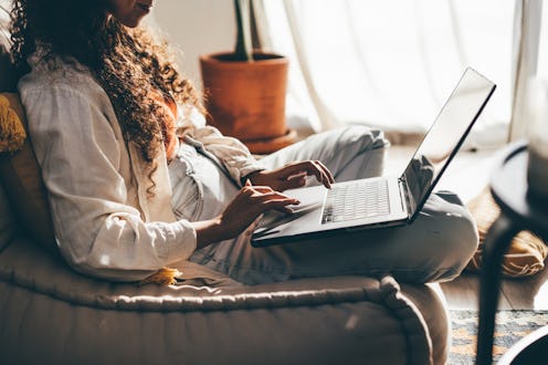Young woman with laptop working in living room.