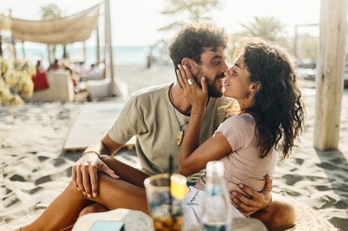 Young happy couple kissing while enjoying in summer day on the beach.