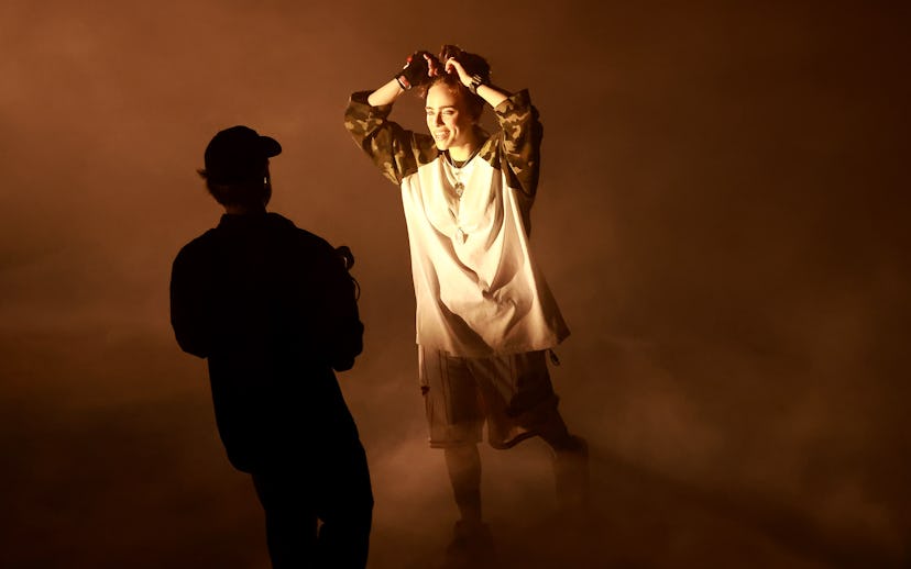 Photographer captures a female model in a foggy room, bathed in warm light, striking a pose with han...