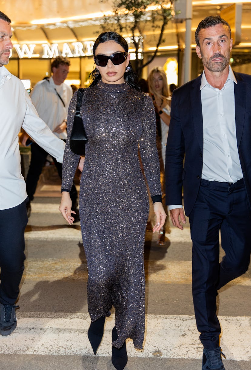CANNES, FRANCE - MAY 16: Charli XCX wears sunglasses, grey glitter dress, black bag outside Magnum W...