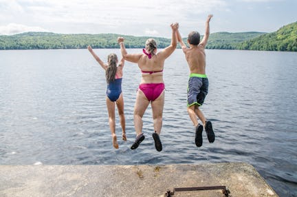 Woman, boy and girl plunging in water lake from the deck during summer day vacations
