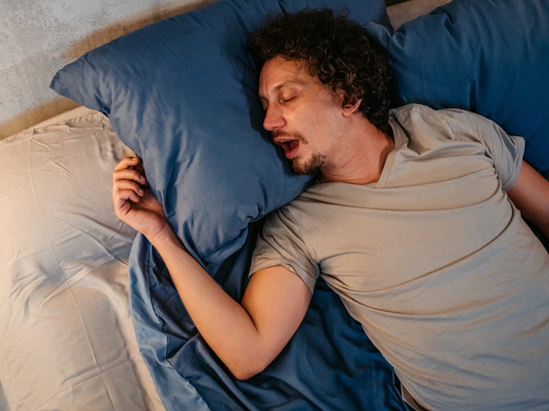 Handsome young man sleeping in the bed at night in his bedroom. Snoring and having breathing problem...