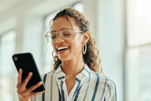 woman laughing at some good jokes on her phone