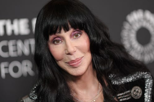 A woman with long black hair and bangs smiles at a camera wearing a sparkly black jacket, against a ...