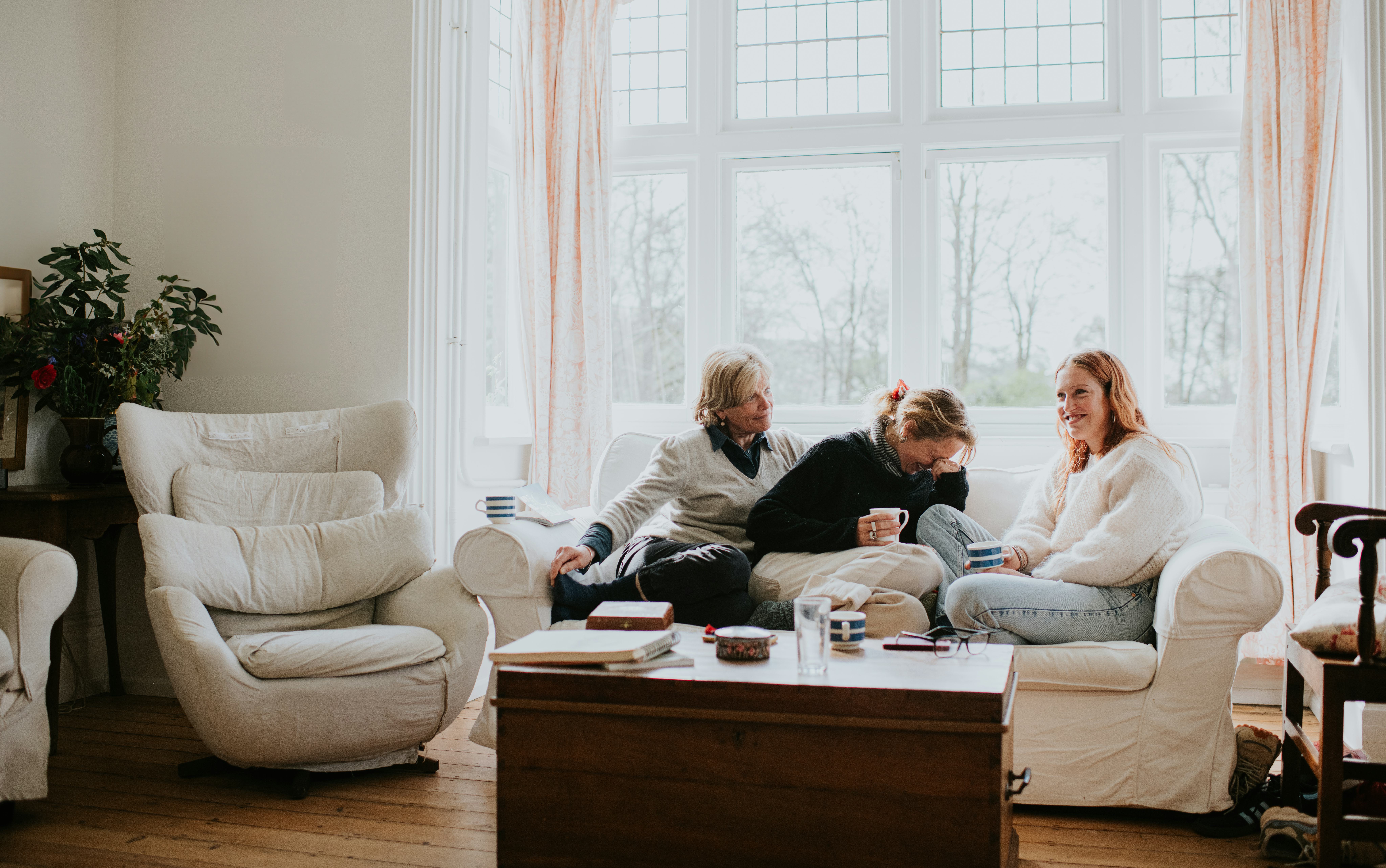 A family of three sit on a couch and ask each other clean Never Have I Ever questions