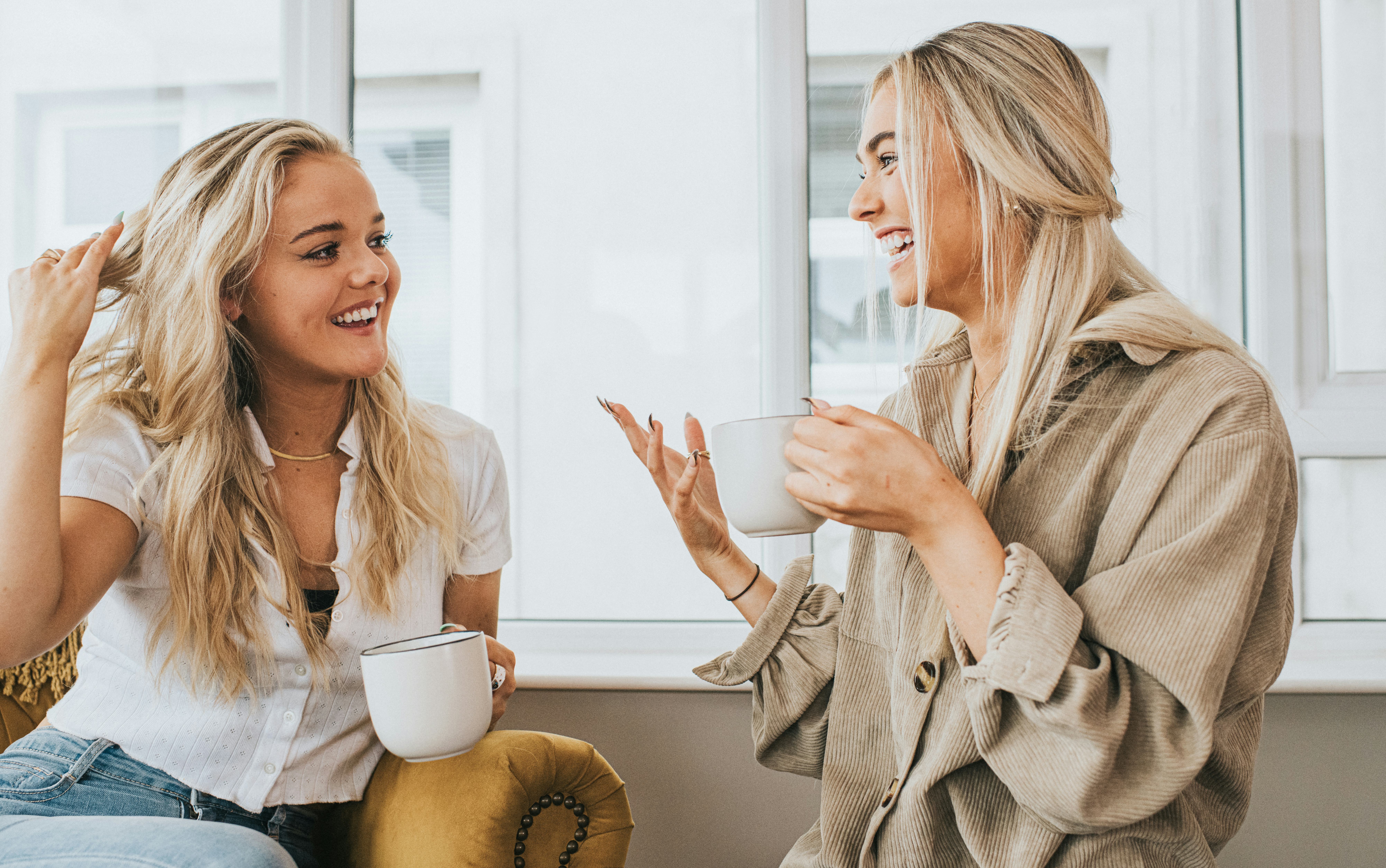 Two female friends asking each other Never Have I Ever questions while drinking from mugs