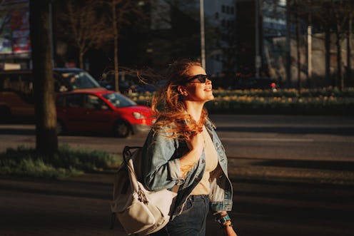 Happy redhead woman relaxing outdoors, exploring and strolling in downtown city street at sunset