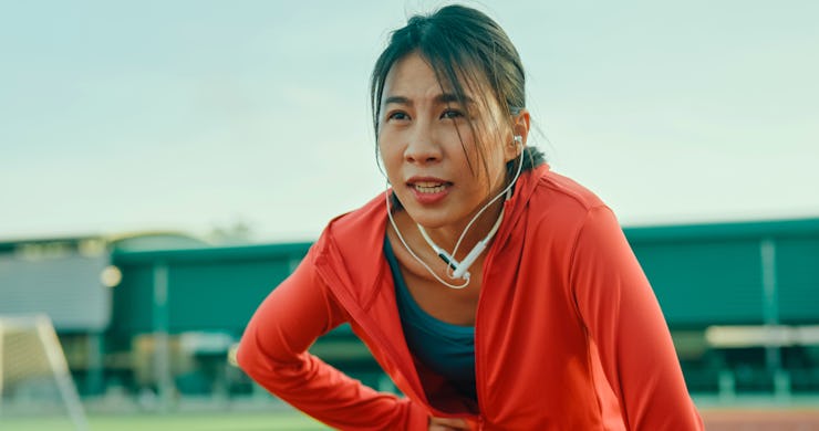 Closeup of young Asian female athlete runner exhausted and tired after running exercise outdoors. He...
