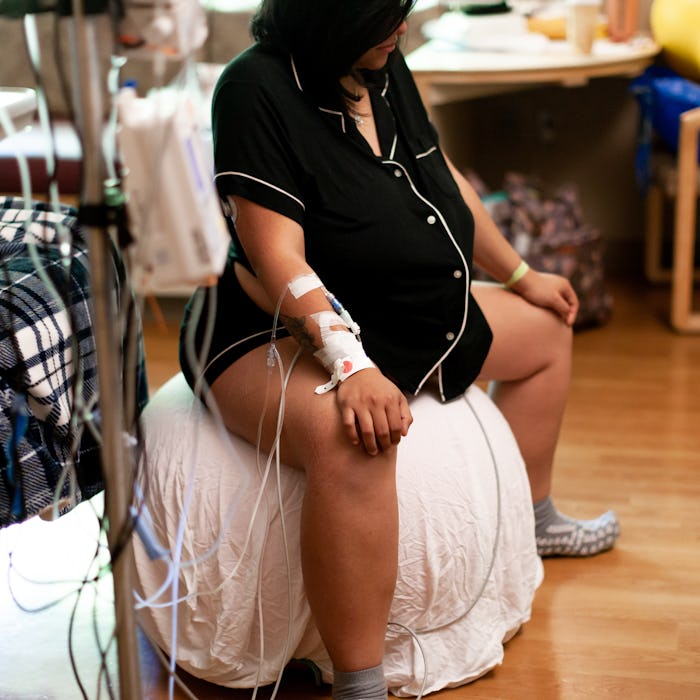 Pregnant woman in a hospital using exercise ball to help induce active labor into child birth.