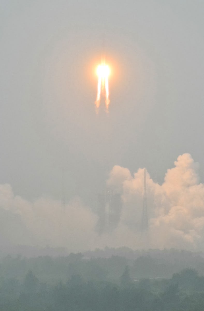 TOPSHOT - A Long March 5 rocket, carrying the Chang'e-6 mission lunar probe, lifts off as it rains a...